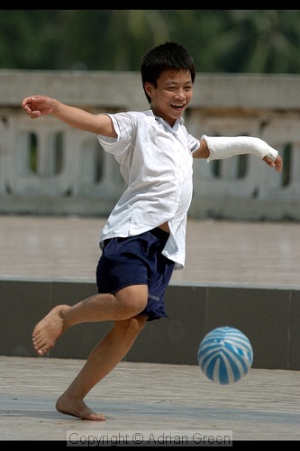 Boy with broken arm playing football in Lenin Park, Hanoi