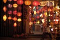 Boy sitting in front of lantern shop during the festival of light in Hoi An