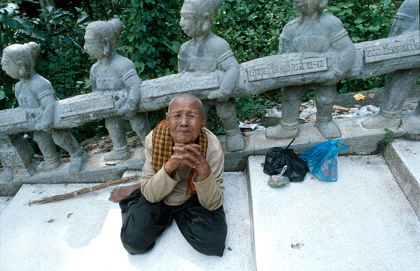 Old woman begs for alms along the steps of Phnom San Tuk