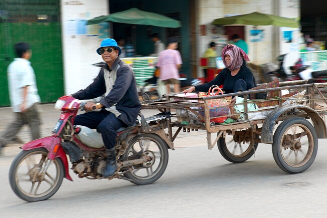Motor cyclist towing his wife on a trailer near Russian Market, Phnom Penh, Cambodia