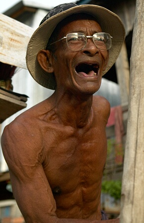 Old man (owner of boa constrictor) laughing near his stilted house, Phnom Penh, Cambodia