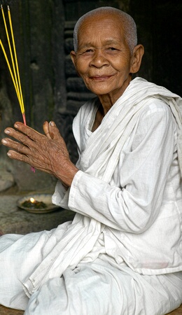 Old lady burning incense at the Bayon, Angkor Complex, Siem Reap, Cambodia