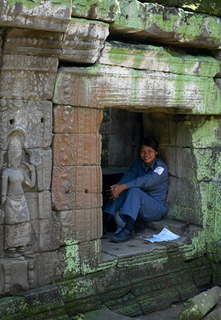 Caretaker resting in a niche at Ta Prohm Temple, Angkor Complex, Siem Reap, Cambodia