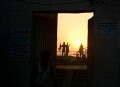 Sunrise over the Ganges, Varanasi. People performing their morning exercises on the roof of a building are visible through a doorway in the wall