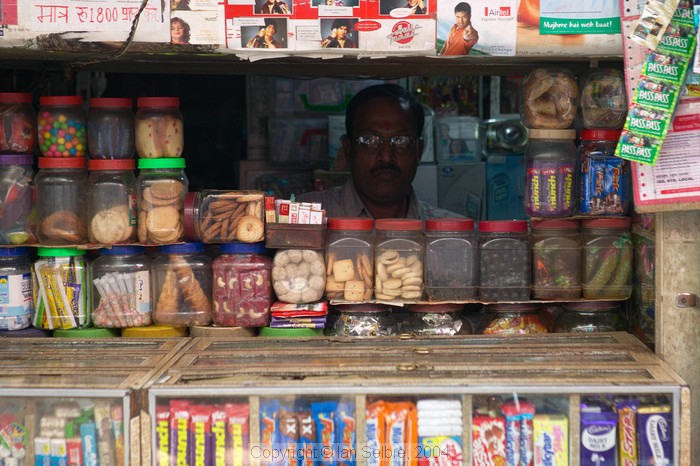 Shopkeeper peers from the darkness of his shop,  old Varanasi