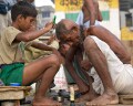 Shaving the heads of children and adults is a symbol of purification before bathing in the Ganges. Here the children are shaving the elders