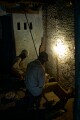 Behind the scenes in old Varanasi the working conditions are not pleasant. These men work in near darkness grinding small metal components.